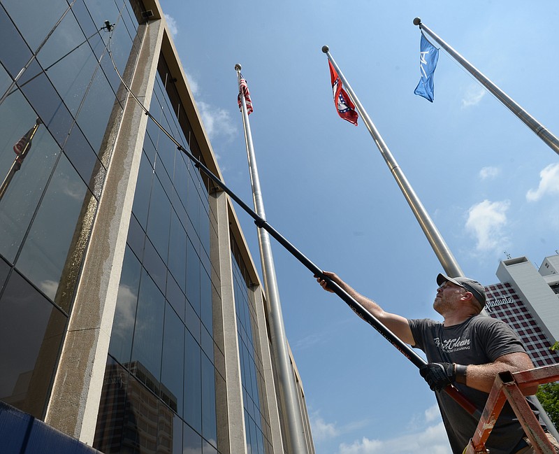 FILE -- Brad Stillings, owner of BrightClean Window Cleaning in Fayetteville, uses a long-handled brush Wednesday, June 3, 2020, to wash the windows of the Arvest Bank building on the Fayetteville downtown square. 
(NWA Democrat-Gazette/Andy Shupe)