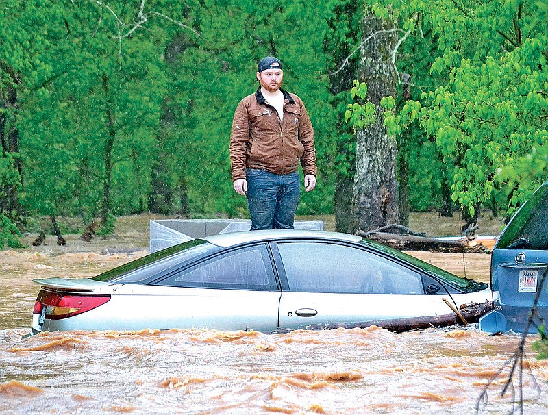Jaxon Douglass, 21, waits Wednesday morning for water rescue personnel to reach him as he stands on concrete blocks outside his grandparents’ home in Little Flock in Benton County. His uncle was swept away by the water but was also rescued. More photos at arkansasonline.com/429/nwarain/.
(Pea Ridge Times/Annette Beard)