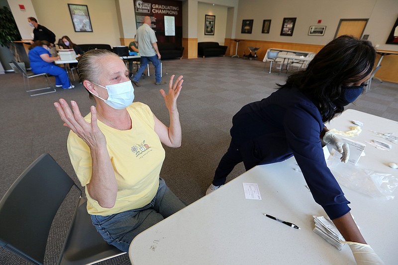 Kathy Davidson throws her hands in the air in celebration after getting her first dose of the Pfizer vaccine from UALR nursing instructor Shelia Brooks during UALR's vaccine clinic put on by Don's Pharmacy on Wednesday, April 28, 2021, at the Jack Stephens Center in Little Rock. (Arkansas Democrat-Gazette/Thomas Metthe)