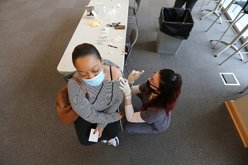 Mia Hampton gets her first dose of the Pfizer vaccine from Jami De La Cruz, a senior nursing student at UALR, during UALR's vaccine clinic put on by Don's Pharmacy on Wednesday, April 28, 2021, at the Jack Stephens Center in Little Rock. (Arkansas Democrat-Gazette/Thomas Metthe)