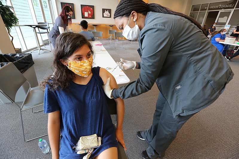 University of Arkansas at Little Rock senior Rebecca Farhat of Fort Smith gets her first dose of the Pfizer vaccine from Simone Kennedy, a junior nursing student at UALR, during UALR's vaccine clinic put on by Don's Pharmacy on Wednesday, April 28, 2021, at the Jack Stephens Center in Little Rock. (Arkansas Democrat-Gazette/Thomas Metthe)