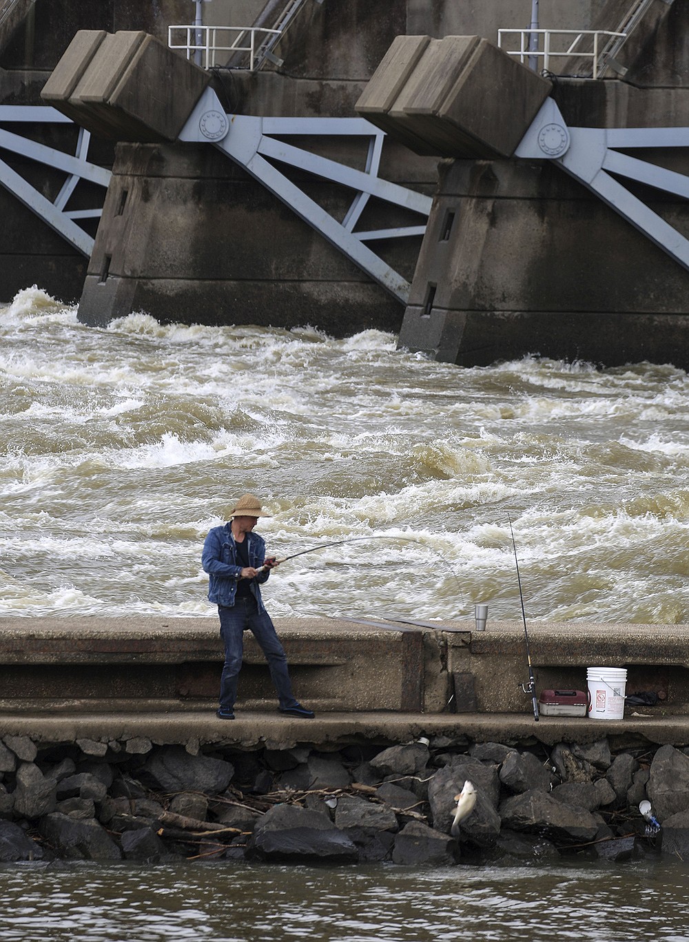 Water rushes through the gates at Murray Lock and Dam on Thursday as a fisherman lands a fish at Cook’s Landing in North Little Rock. The U.S. Army Corps of Engineers Little Rock District issued a small-craft advisory for the McClellan-Kerr Arkansas River Navigation System in Arkansas. Rainfall in eastern Oklahoma and western Arkansas is raising water flows. Small-craft advisories are issued when flows exceed 70,000 cubic feet per second.
(Arkansas Democrat-Gazette/Staton Breidenthal)