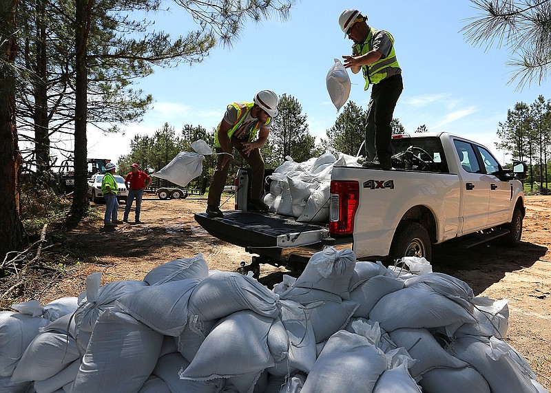 U.S. Army Corps of Engineers Ranger Aaron Winchester (right) and maintenance technician Hayden Gadberry unload sandbags Friday at the Perry County levee. The Corps is making emergency repairs on the 3-mile-long levee to prevent flooding this weekend. The levee is still undergoing repairs after it was breached 19 times during 2019 flooding.
(Arkansas Democrat-Gazette/Thomas Metthe)