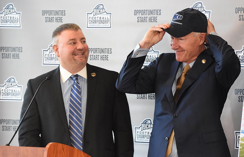 National Junior College Athletic Association President Christopher Parker (left) watches Arkansas Gov. Asa Hutchinson try on an NJCAA cap during a news conference Friday announcing that the two-year college football championship games will be played four times in three years at War Memorial Stadium in Little Rock starting June 5.
(Arkansas Democrat-Gazette/Staci Vandagriff)