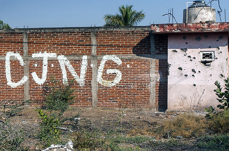 A bullet-riddled wall bearing the initials of the criminal group Cartel Jalisco Nueva Generacion sits at the outskirts of Aguililla.
(Tribune News Service/AFP/Getty/Enrique Castro)