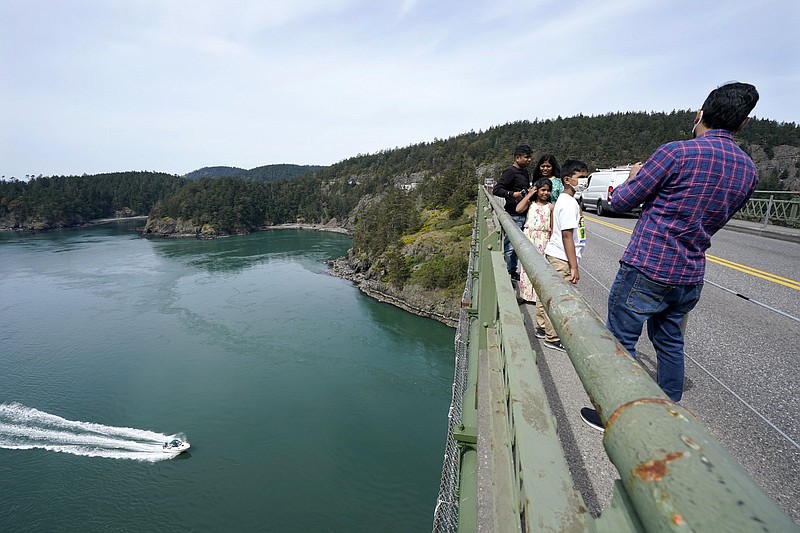 A family walks Thursday along the narrow sidewalk of the Deception Pass Bridge, a 976-foot span about 180-feet above the water below, where work is underway to replace corroded steel and paint on the structure in Deception Pass, Wash.
(AP/Elaine Thompson)