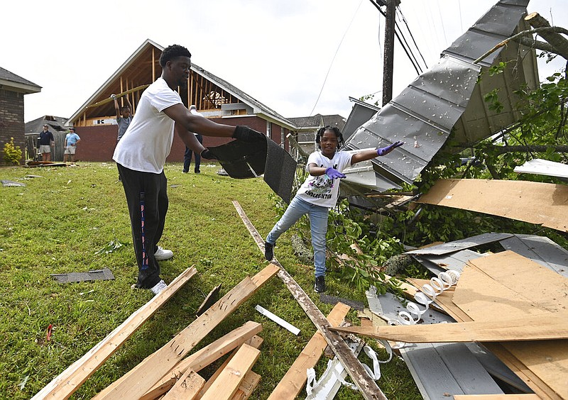 Derrick Pounds and his daughter, Madison, 6, clean up debris around their residence on Elvis Presley Drive in Tupelo, Miss., Monday, May 3, 2021. (AP/Thomas Graning)