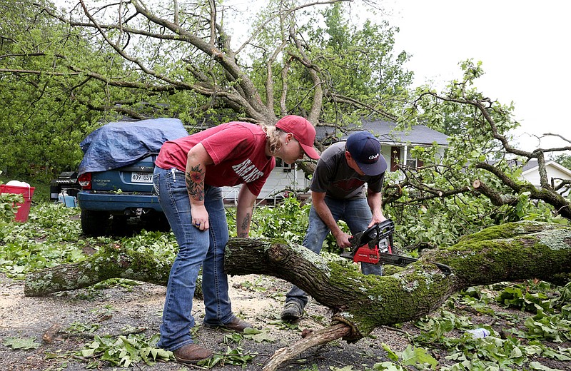 Barbara Selman and her brother Dewayne Selman cut the limbs and branches Tuesday, May 4, 2021, from a tree that fell from his yard across the street and onto his neighbors house on North 8th Street following strong winds overnight in Van Buren. The Crawford County Department of Emergency Management said damage throughout the county as a result of the storm was extensive and asked residents not to go out, except in case of an emergency. Check out nwaonline.com/210505Daily/ and nwadg.com/photos for a photo gallery..(NWA Democrat-Gazette/David Gottschalk)