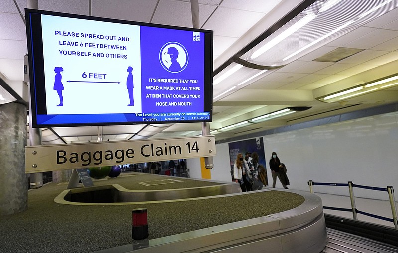 This electronic sign on Dec. 10 in the terminal of Denver International Airport warns travelers to  maintain a social distance.
(AP/David Zalubowski)