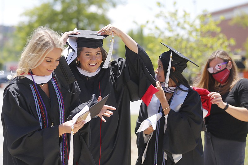 Kathryn Lindner (from left), Lindsay Terreri and Maria Hall are helped by Laura Moix, a member of the commencement staff, Thursday before entering the University of Arkansas 2021 graduate degree commencement ceremony at Bud Walton Arena on campus in Fayetteville. The ceremony was the first of 19 UA commencements that will take place through Saturday.
(NWA Democrat-Gazette/David Gottschalk)
