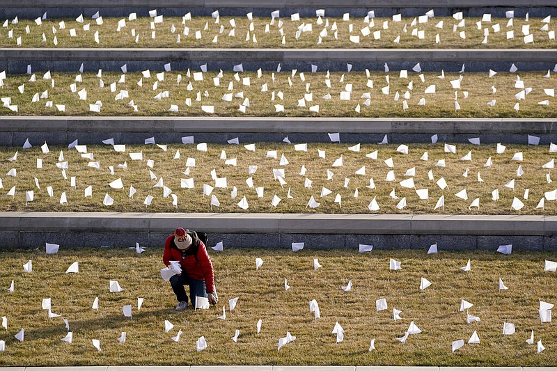A man places flags at the National World War I Museum and Memorial in Kansas City, Mo., in this Jan. 19, 2021, file photo. The 1,665 flags represented the area residents who had died at that point in the coronavirus pandemic. (AP/Charlie Riedel)