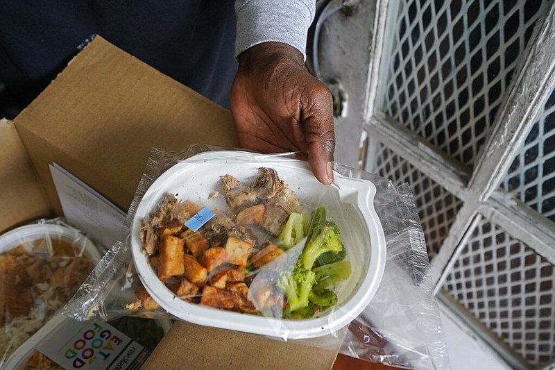 Jackie Robinson shows the contents of meal boxes he received that were delivered by Revolution Foods in New Orleans on Thursday, Feb. 11, 2021. Robinson, a 66-year-old retired cook who once worked at a French Quarter restaurant in New Orleans, struggled to get by on his Social Security benefits before the pandemic, occasionally visiting a food pantry. But over the summer he signed up for a city-run delivery program and now gets two meals a day, seven days a week. (AP/Gerald Herbert)