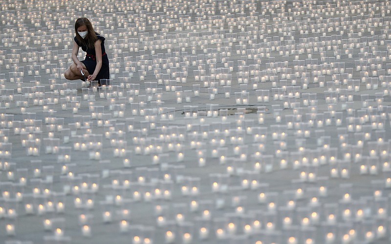 Woman lights a candle to commemorate victims of the COVD-19 pandemic at the Prague Castle in Prague, Czech Republic, Monday, May 10, 2021. The Czech Republic is massively relaxing its coronavirus restrictions as the hard-hit nation pays respect to nearly 30,000 dead. (AP Photo/Petr David Josek)