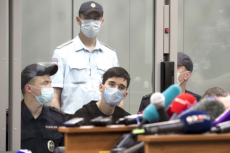 School shooting suspect Ilnaz Galyaviyev (center, seated) sits behind a glass partition Wednesday surrounded by police officers during a court hearing in Kazan, Russia.
(AP/Dmitri Lovetsky)