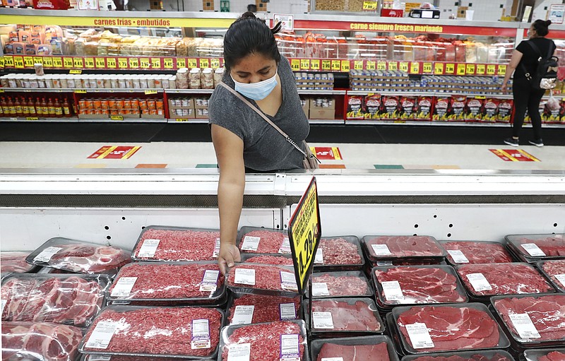 FILE - In this April 29, 2020 file photo, a shopper wears a mask as she looks over meat products at a grocery store in Dallas.   Wholesale prices rose a higher-than-expected 0.6% in April, driven by a sharp rise in food costs.   The increase, reported Thursday, May 13, 2021,  by the Labor Department, followed a sizable 1% advance in March.(AP Photo/LM Otero, File)