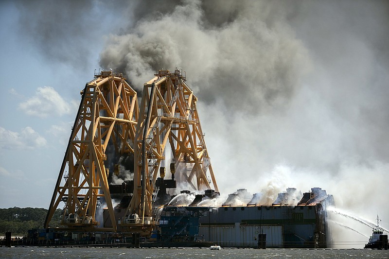 Firefighters on tug boats Friday work to extinguish a blaze on an overturned cargo ship being dismantled in Brunswick, Ga.
(AP/Stephen B. Morton)