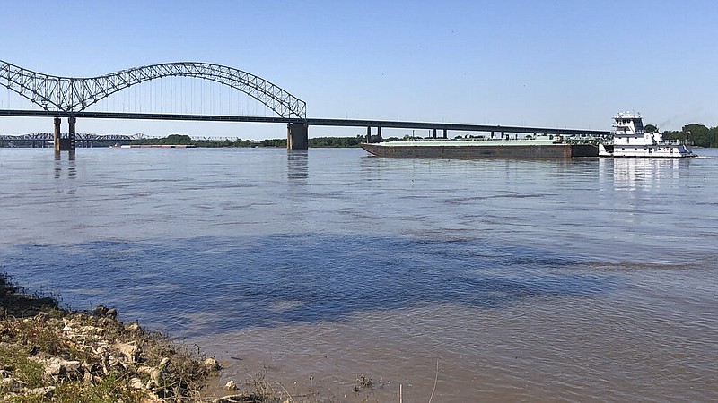 A boat hauling barges down the Mississippi River moves toward the Interstate 40 bridge linking Tennessee and Arkansas on Friday, May 14, 2021, in Memphis. (AP/Adrian Sainz)