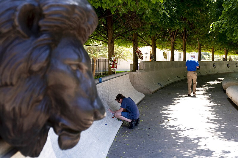 Ryan Lowe, 12, of Colorado Springs, Colo., makes an engraving of the name of former El Paso County, Colo., Detective Micah Flick on the wall at the National Law Enforcement Officer Memorial in Washington on Thursday, May 13, 2021. Flick worked with Lowe's father. The names of the 394 fallen officers have been added to the wall in 2020 and were read during a virtual candlelight vigil that night as part of Police Week. (AP/Andrew Harnik)