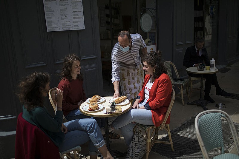 A waiter serves customers Wednesday at a cafe in La Ciotat in southern France as cafe and restaurant terraces reopened after months of lockdown. In a formal turning point, the European Union is planning to open its borders to vaccinated Americans and others in coming weeks.
(AP/Daniel Cole)