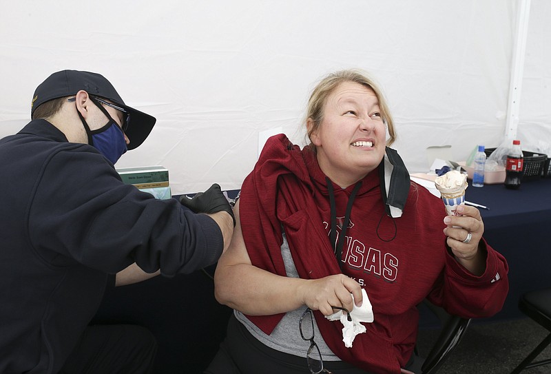 Firefighter paramedic Logan Miller (from left) administers a covid-19 vaccine to Tricia Redus of Bella Vista, Friday, May 7, 2021 at a pop-up clinic at the downtown square in Bentonville. 
(NWA Democrat-Gazette/Charlie Kaijo)