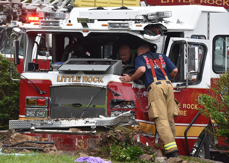 The Little Rock Fire Department firefighter leans into the cab of one of two department trucks involved in a collision Thursday afternoon at South University Avenue and West 28th Street. The crash left six firefighters with non-life-threatening injuries. More photos at arkansasonline.com/521lrfd/.
(Arkansas Democrat-Gazette/Staci Vandagriff)