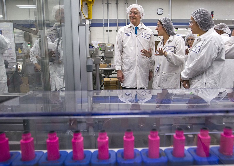 Gov. Asa Hutchinson (left) tours the L'Oreal USA manufacturing and distribution facility in North Little Rock in this July 2017 file photo. (Arkansas Democrat-Gazette file photo)