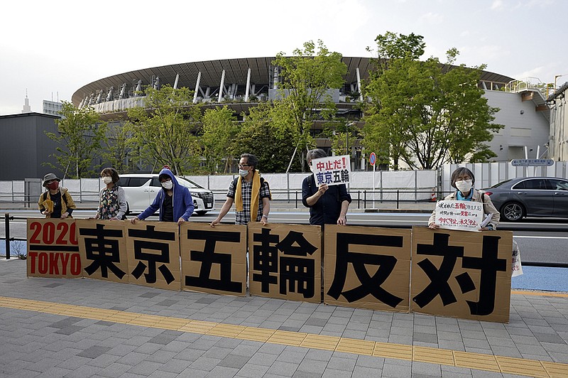 Protesters hold banners near the National Stadium, the main stadium for the Tokyo 2020 Olympic Games, May 9 in Tokyo.
(Bloomberg/Kiyoshi Ota)