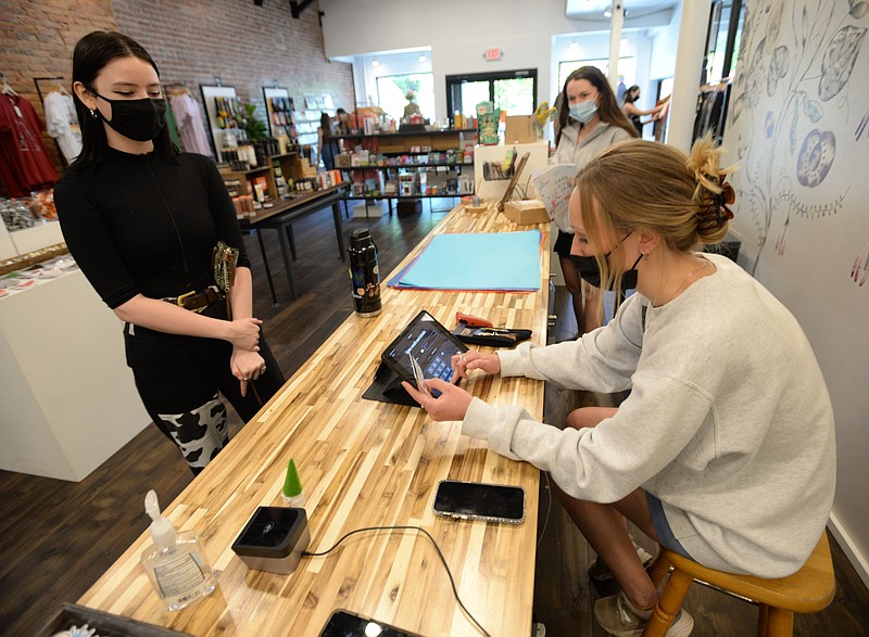 Rebecca Christie (right), a retail associate, rings up a purchase Friday, May 28, 2021, for customer Riley Parker (left) of Rogers as manager Liz Allee stands nearby at Stache, a store in downtown Fayetteville. The Fayetteville City Council is considering calling an Aug. 10 special election to renew the cityÕs 1-cent sales tax. Visit nwaonline.com/210530Daily/ for today's photo gallery.
(NWA Democrat-Gazette/Andy Shupe)