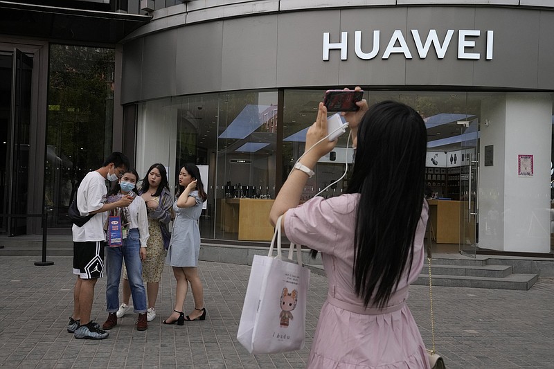 Shoppers stand outside a Huawei store Wednesday in Beijing. Huawei is offering its HarmonyOS mobile operating system on its handsets.
(AP/Ng Han Guan)