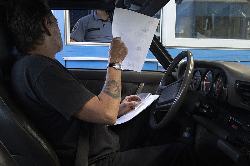 Enrico Dagnino, a traveler from France, passes documents to a Croatian border officer Wednesday at the Bregana crossing between Croatia and Slovenia.
(AP/Darko Bandic)