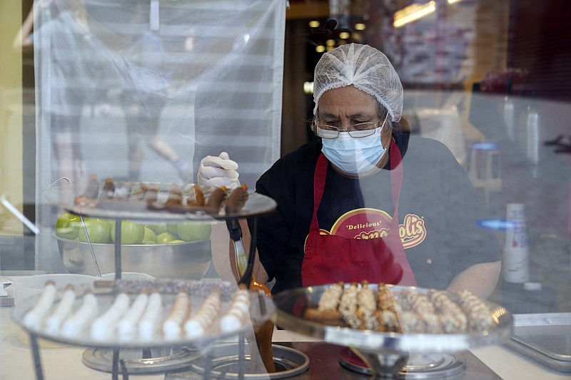 FILE - In this May 14, 2021, file photo, a worker wears a mask while prepares desserts at the Universal City Walk, in Universal City, Calif. California workplace regulators are considering Thursday, June 3, 2021, whether to end mask rules if every employee in a room has been fully vaccinated against the coronavirus, frustrating business groups by eying a higher standard than the state plans to soon adopt for social settings. (AP Photo/Marcio Jose Sanchez, File)