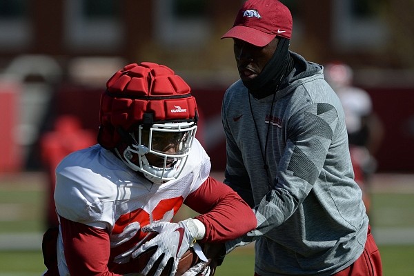 Arkansas assistant coach Jimmy Smith hands the ball off to running back Josh Oglesby.