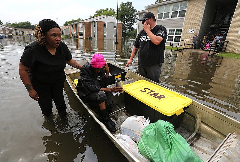 Tamika Harris (left) and Stuttgart police officer Jacob Cain help Betsy Horton get out of the Stuttgart Apartment Complex on Wednesday after the complex flooded overnight. More photos at arkansasonline.com/610flooding/.
(Arkansas Democrat-Gazette/Thomas Metthe)