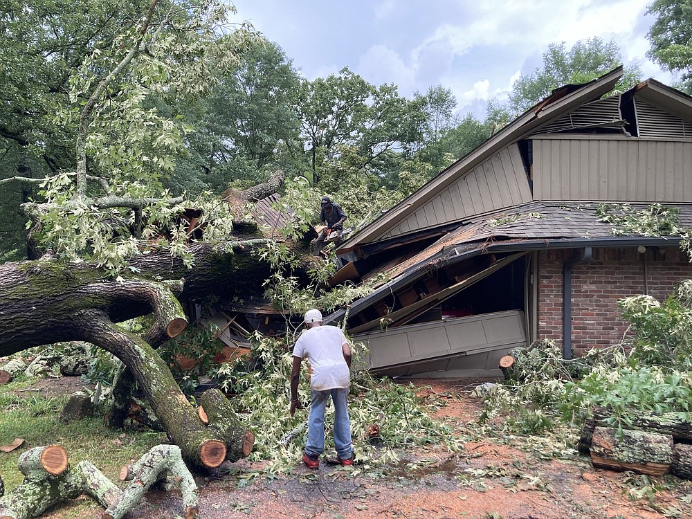 Workers with Sylvester Parker Tree Cutting Service work Wednesday to remove one of two trees that fell on this home on Cherry Street.
(Pine Bluff Commercial/Byron Tate)