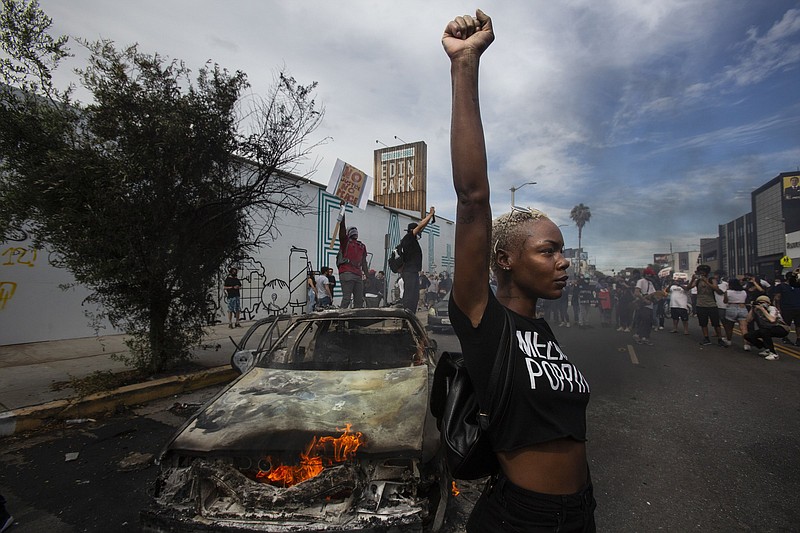 A woman raises her fist next to a burning police vehicle in Los Angeles during protests in May 2020 over the death of George Floyd. The image was part of a series of photographs by The Associated Press that won the 2021 Pulitzer Prize for breaking news photography.
(AP/Ringo H.W. Chiu)