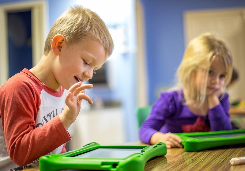 Caleb Braschler and Kate Pearson, then both age 4, work on tablet computers at the Siloam Springs Children’s Center in this November 2014 file photo.