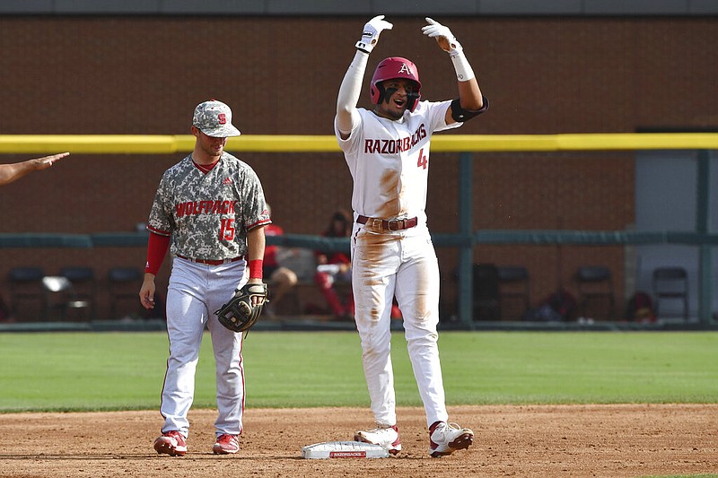 Arkansas baserunner Jalen Battles (4) celebrates in front of North Carolina State infielder J.T. Jarrett (15) after reaching second base in the second inning of their NCAA college baseball super regional game in Fayetteville on Friday, June 11, 2021. (AP/Michael Woods)