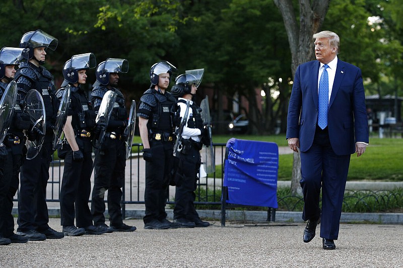 FILE - In this June 1, 2020 file photo, President Donald Trump walks past police in Lafayette Park after visiting outside St. John's Church across from the White House in Washington. An internal investigation has determined that the decision to clear racial justice protestors from an area in front of the White House last summer was not influenced by then-President Donald Trump’s plans for a photo opportunity at that spot. (AP/Patrick Semansky)