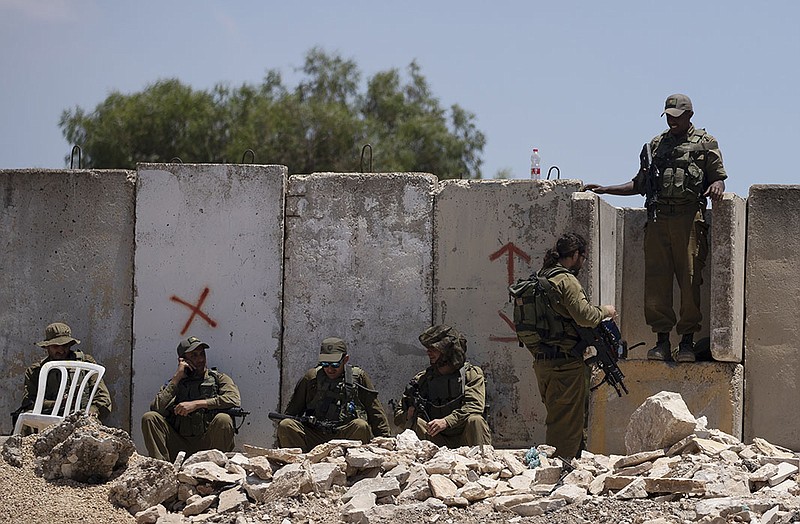 Israeli soldiers rest at the site of a vehicle attack Wednesday near Hizmeh Junction in the West Bank. Soldiers shot and killed a Palestinian woman who Israeli officials said tried to ram her car into a unit guarding a West Bank construction site.
(AP/Maya Alleruzzo)