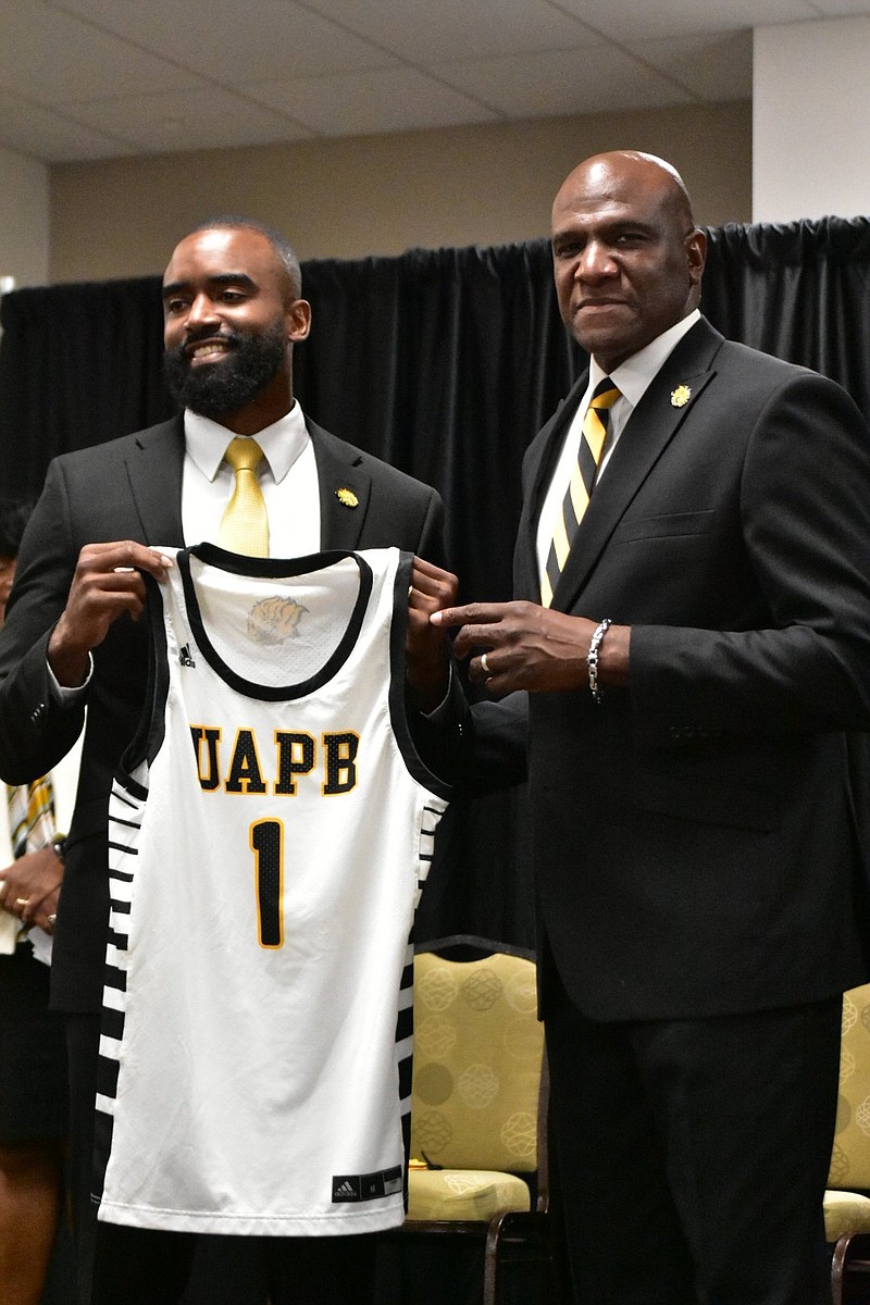 New UAPB men's basketball Coach Solomon Bozeman, left, receives a jersey from recently promoted Athletic Director Chris Robinson at the start of Bozeman's introductory news conference Tuesday, June 15, 2021. (Pine Bluff Commercial/I.C. Murrell)