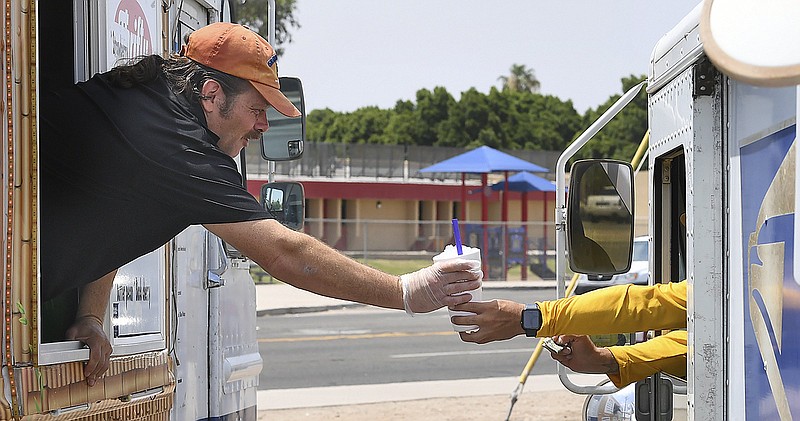 Aaron Denison (left), owner of Yuma Snow On The Go, hands a cup of ice water to a U.S. Postal Service worker who stopped in for some cool refreshment Thursday in Yuma, Ariz.
(AP/The Yuma Sun/Randy Hoeft)