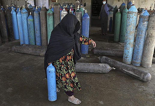 An Afghan woman carries an oxygen cylinder from a privately owned oxygen factory Saturday in Kabul. Hospitals are rationing oxygen supplies as the country even runs low on empty cylinders.
(AP/Rahmat Gul)