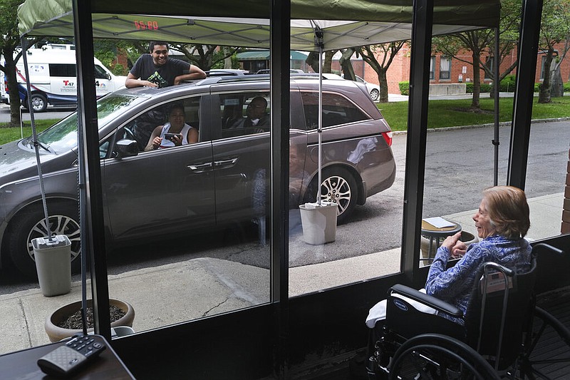 Gloria DeSoto (right), 92, visits with her family in their car from a window of the Hebrew Home at Riverdale, where she lives, in New York in this June 11, 2020, file photo. Strict rules on visits to nursing homes and long-term care facilities were imposed at the beginning of the coronavirus pandemic in March 2020. (AP/Seth Wenig)