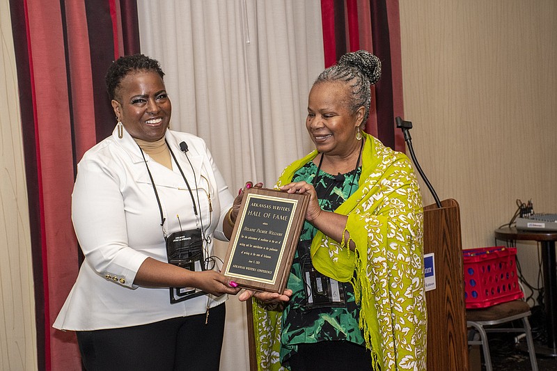 Helaine Williams receives a plaque signifying she’s been inducted into the Arkansas Writers’ Hall of Fame from Janis Kearney. 
(Arkansas Democrat-Gazette/Cary Jenkins)