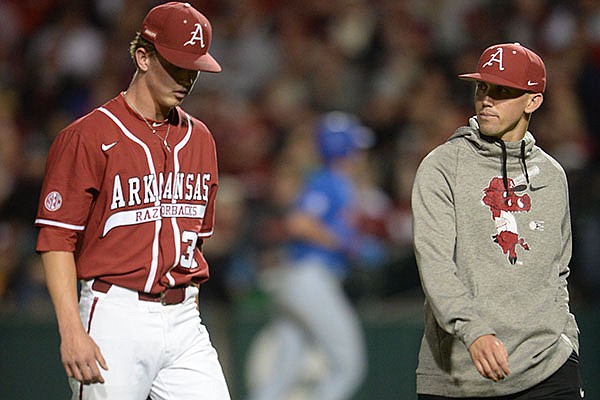 Arkansas pitcher Peyton Pallette (left) walks off the field with trainer Corey Wood after injuring his elbow during a game against Florida on Friday, May 21, 2021, in Fayetteville.