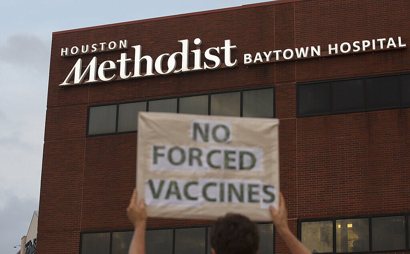 A person holds a sign to protest mandatory vaccinations at Houston Methodist Hospital in Baytown, Texas, in this June 7, 2021, file photo. More than 150 Houston Methodist system employees who refused to get a covid-19 vaccine were fired or resigned after a judge dismissed an employee lawsuit over the vaccine requirement, Houston Methodist system spokesperson Gale Smith said Tuesday, June 22, 2021. (Yi-Chin Lee/Houston Chronicle via AP)