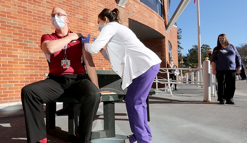 Buster McCall, administrator at Arkansas State Veterans Home at Fayetteville, receives a covid-19 vaccine shot Jan. 5 from Falon Lacey, a pharmacist with AllCare Pharmacy, in front of the facility in Fayetteville. The city's Board of Health discussed ways to better reach the 70 and older population for vaccine distribution. (File photo/NWA Democrat-Gazette/David Gottschalk)