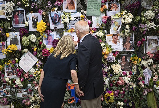 President Joe Biden and first lady Jill Biden look Thursday at a memorial for the victims of the condo collapse in Surfside, Fla. Biden met with grieving families and searchers after work was temporarily halted out of concerns about the stability of the section still standing. More photos at arkansasonline.com/72bidenfla/. (The New York Times/Tom Brenner)