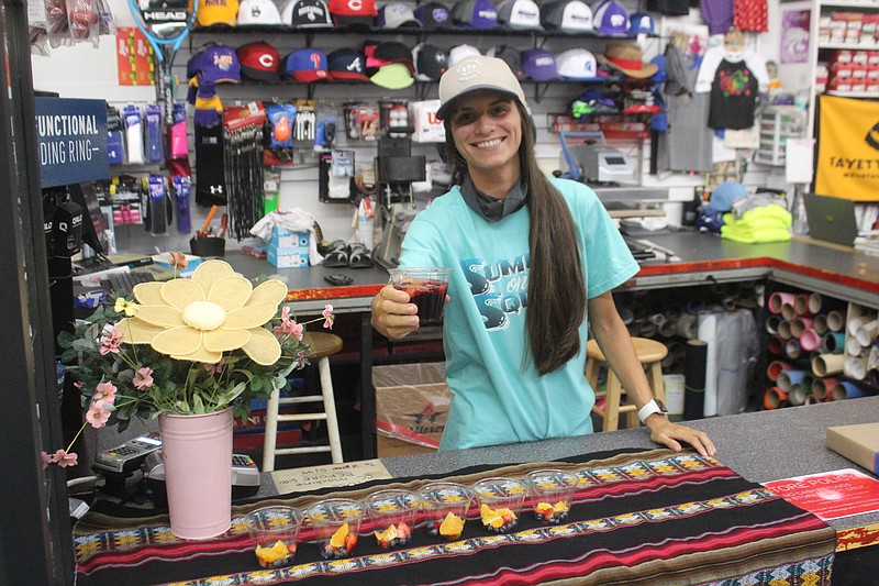 Brooklyn Greer at Sports Alley showcases the store’s First Thursday Spanish theme, offering sangrias to customers. (Matt Hutcheson/News-Times)