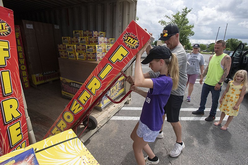 Abbi Bowerman, 11, helps her dad, Jeff Bowerman load a package of fireworks Wednesday June 30, 2021 for customer Josh Sly of Bella Vista and his daughter Lilly, 7, at Sams Club in Fayetteville. The family, including Kim Bowerman, center, has been selling fireworks at the same location for 6 years. Visit nwaonline.com/21000701Daily/ and nwadg.com/photo. (NWA Democrat-Gazette/J.T. Wampler).